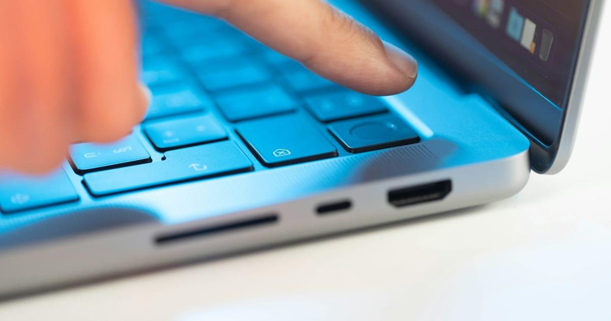 A fingertip resting on a laptop key, a moment before pressing it