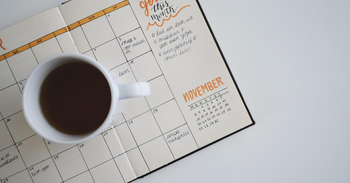 Open planner showing a November calendar next to a cup of coffee