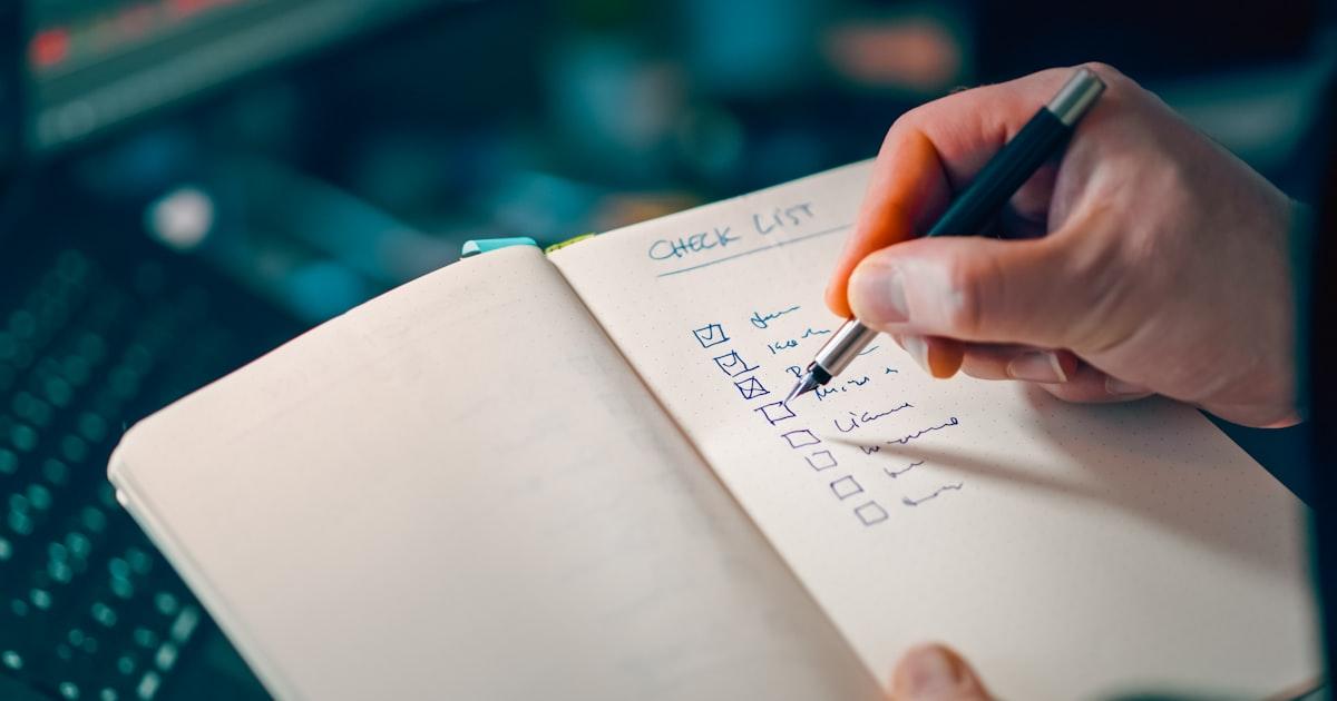 Hand ticking items off a checklist in a notebook